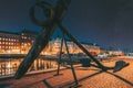 Helsinki, Finland. Old Anchor On Pier With View Of Pohjoisranta Street In Evening Night Illuminations. Colourful Night