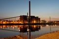 An old red brick power plant building casting reflections on the water Royalty Free Stock Photo