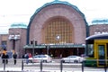 Helsinki station square, green passenger tram of Helsinki City Transport rides along city street, people walking along winter