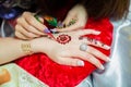 Henna design tattoo. Women applying roses henna tattoo on women hands. Woman draws mehendi on the hands . Artist applying henna ta