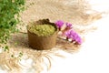 Henna powder for dyeing hair and eyebrows and drawing mehendi on hands, with green leafs, pink flowers and sackcloth