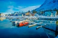 Henningsvaer, Norway - April 04, 2018: Outdoor view of small fishing boats in a fishing port with a mountain reflection