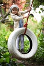 Her favourite part of the garden. Portrait of a cute little girl playing on a tire swing in the garden. Royalty Free Stock Photo