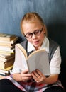 Her friends call her a bookworm. A cute blonde girl reading intently in class surrounded by books. Royalty Free Stock Photo