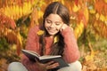 Her hobby is reading. Cute small child reading book on autumn day. Adorable little girl enjoy English literature Royalty Free Stock Photo