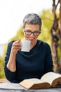 Her idea of the perfect day. an attractive senior woman reading her bible while drinking coffee outside. Royalty Free Stock Photo