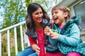 Her laughter warms her mothers heart. a mother watching her daughter blow bubbles outside.