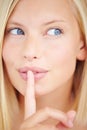 Her lips are sealed. Portrait of a young woman holding her finger in front of her lips. Royalty Free Stock Photo