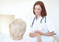 Her presence is a part of their recovery. Friendly mature nurse comforts her elderly patient by holding her hand