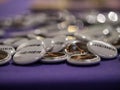 She/Her pronouns on white pin badge on purple table with shallow depth pot field.