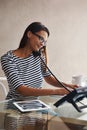 Her small business is flourishing. a young businesswoman multi-tasking at her office desk.