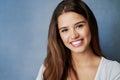 Her smile makes everything alright. Studio shot of an attractive young woman posing against a gray background.