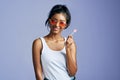 Her style is pretty sweet. Studio portrait of a beautiful young woman sucking on a lollipop against a purple background. Royalty Free Stock Photo