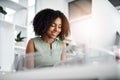 Her workday is going really well. Shot of a young businesswoman working at her desk in a modern office.