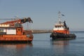 Greek tugboat and crew coming alongside a crane barge to move the vessel out of port.