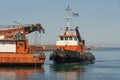 Greek tugboat and crew coming alongside a crane barge to move the vessel out of port.