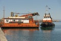 Greek tugboat and crew coming alongside a crane barge to move the vessel out of port.