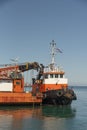 Greek tugboat alongside a crane barge to move the vessel out of port.