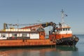 Greek tugboat coming alongside a crane barge to to move the vessel out of port.