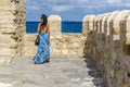 Heraklion, Crete Island, Greece. A young woman in blue dress on the roof of Koules fortress admires the view of the sea