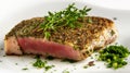 Herb-crusted tuna steak, medium rare, with fresh greens on a white plate