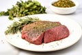 herb rub beef steak on a white dinner plate uncooked