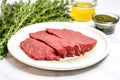 herb rub beef steak on a white dinner plate uncooked