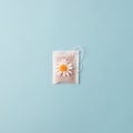 Herbal alternative medicine series: Chamomile flowers and teabags on blue background. Seasonal anti-depression, stomach and colds