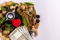Herbal black tablets, stethoscope, money bills and heart shape with spices on white background Royalty Free Stock Photo
