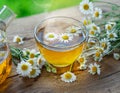 Herbal chamomile tea and chamomile flowers near teapot and tea glass on wooden table. Countryside background Royalty Free Stock Photo