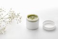 Herbal dermatology cosmetic hygiene green cream with flowers. skincare product in container on white background. Skincare cosmetic