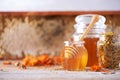 Herbal honey in jar with dipper, honeycomb, bee pollen granules, calendula flowers on grey background