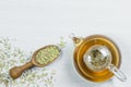 Herbal infusion fennel tea in glass tea pot with dried fennel seeds in wooden shovel on white rustic table Royalty Free Stock Photo
