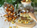 Herbal medicinal tea made from dried flowers of calendula and marigolds on a wooden table and with green leaves in the background. Royalty Free Stock Photo