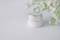 Herbal organic natural dermatology cosmetic hygienic cream with flowers skincare product in glass jar on pastel blue background Royalty Free Stock Photo