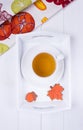Herbal tea and autumn gingerbread in the form of maple leaf and acorn on a white wooden background. Top view