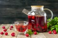 Herbal tea with berries, raspberries, mint leaves and hibiscus flowers in glass teapot and cup on wooden table Medicine for cold Royalty Free Stock Photo