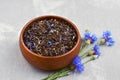 Herbal tea blend with dried cornflower petals in wooden bowl with fresh cornflowers