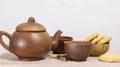 herbal tea in a ceramic brown teapot with cups and a wooden bowl with cookies on a white table background