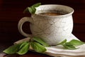 Herbal tea in a ceramic cup and salvia leaves on dark brown wood