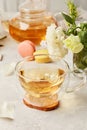 Herbal tea cup and macaron desserts, aesthetic tea time in biophilic interior among white flowers. Feminine calm