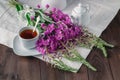 Herbal tea in a glass cup, fresh flowers fireweed against the da