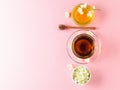 Herbal tea, honey, Jasmine flowers and a wooden spoon on a pink table. Flat lay.