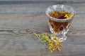 Cup of herbal tea from Hypericum: tincture or decoction of St Jonh`s wort grass in crystal glass on black table. St. John`s wort Royalty Free Stock Photo