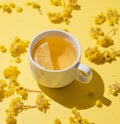 Herbal tea with immortelle and lemon in a white cup on a yellow background close up