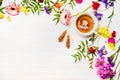 Herbal tea laid out beside fresh colorful spring flowers sugar sticks, Border, place for text