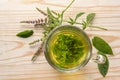 Herbal tea made from fresh peppermint leaves in a glass cup and some flower stems on a rustic light wood table, copy space, high Royalty Free Stock Photo