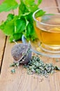 Herbal tea from melissa in cup with strainer on board Royalty Free Stock Photo