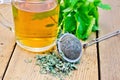 Herbal tea with mint in mug with strainer on board Royalty Free Stock Photo