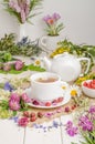 Herbal tea with rosehip, chamomile and clover in a white cup on a wooden table with flowers Royalty Free Stock Photo